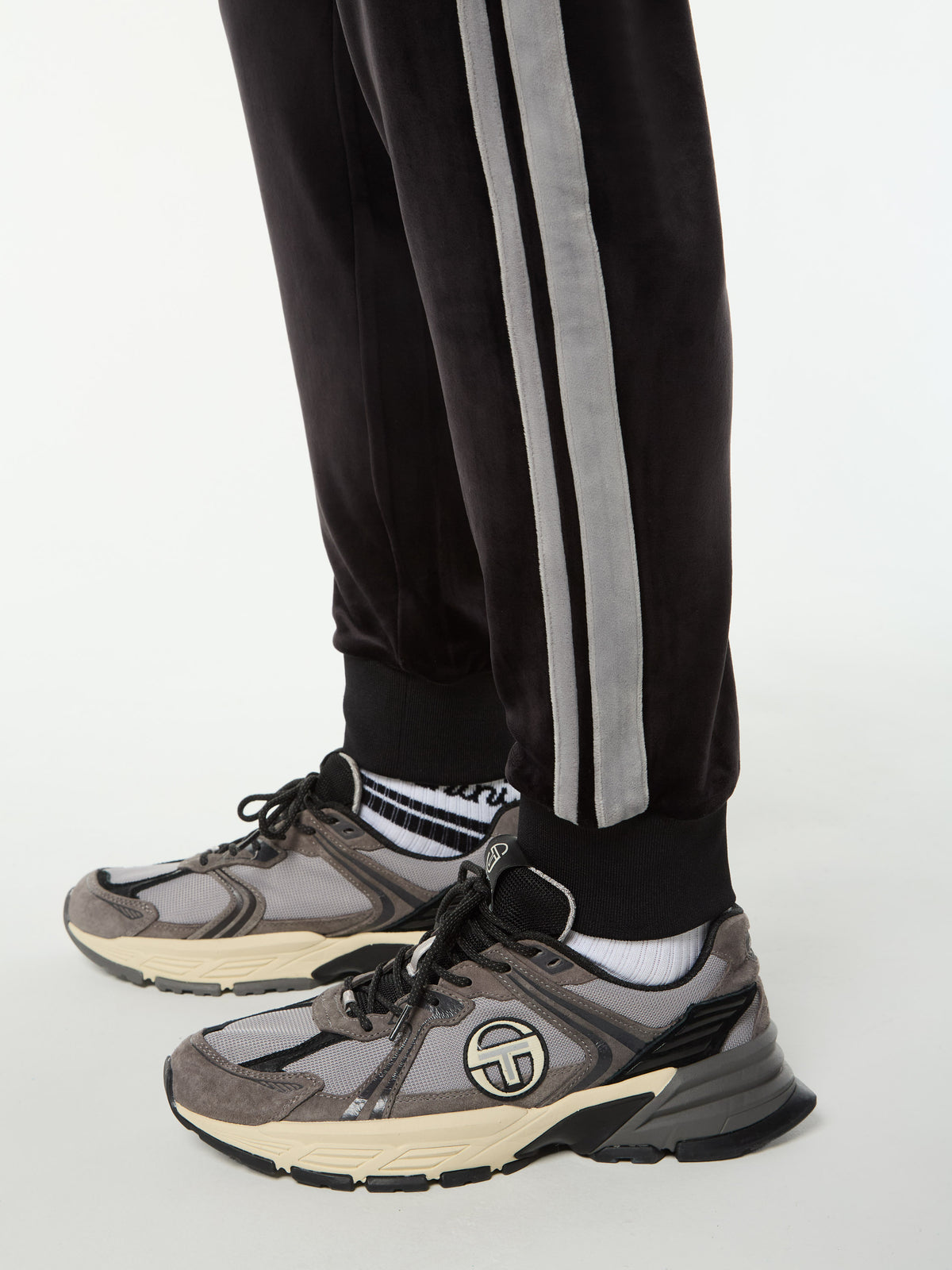 Close-up of the ribbed cuff and gray side stripes on the Damarindo Velour Track Pant in Black Beauty.