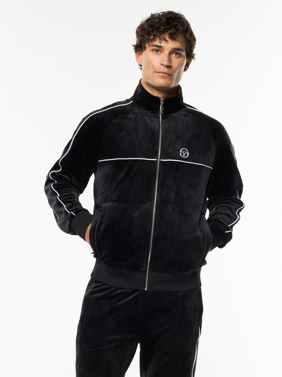 Model wearing the Lioni Velour Track Jacket in Black Beauty with white piping, front upper body view.