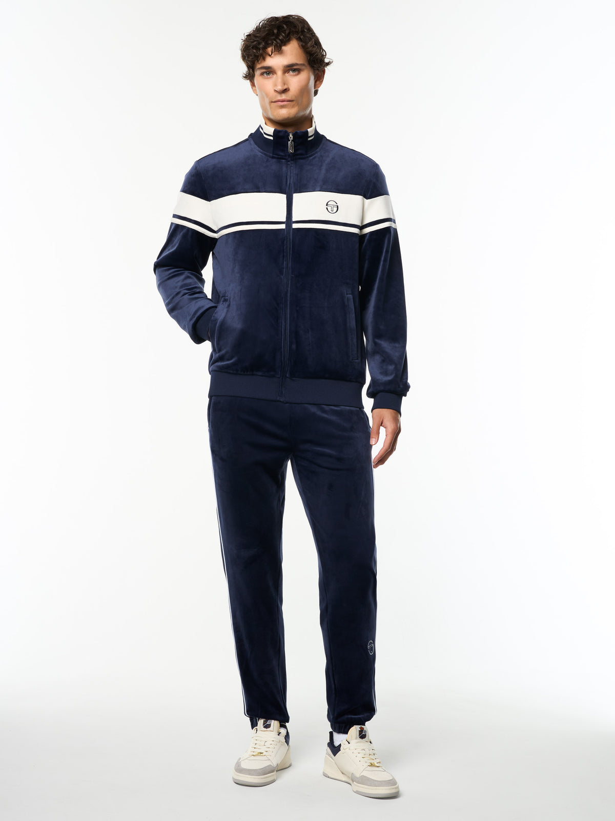 Model wearing the Damarindo Velour Track Jacket and matching pants in Maritime Blue, full body front view.