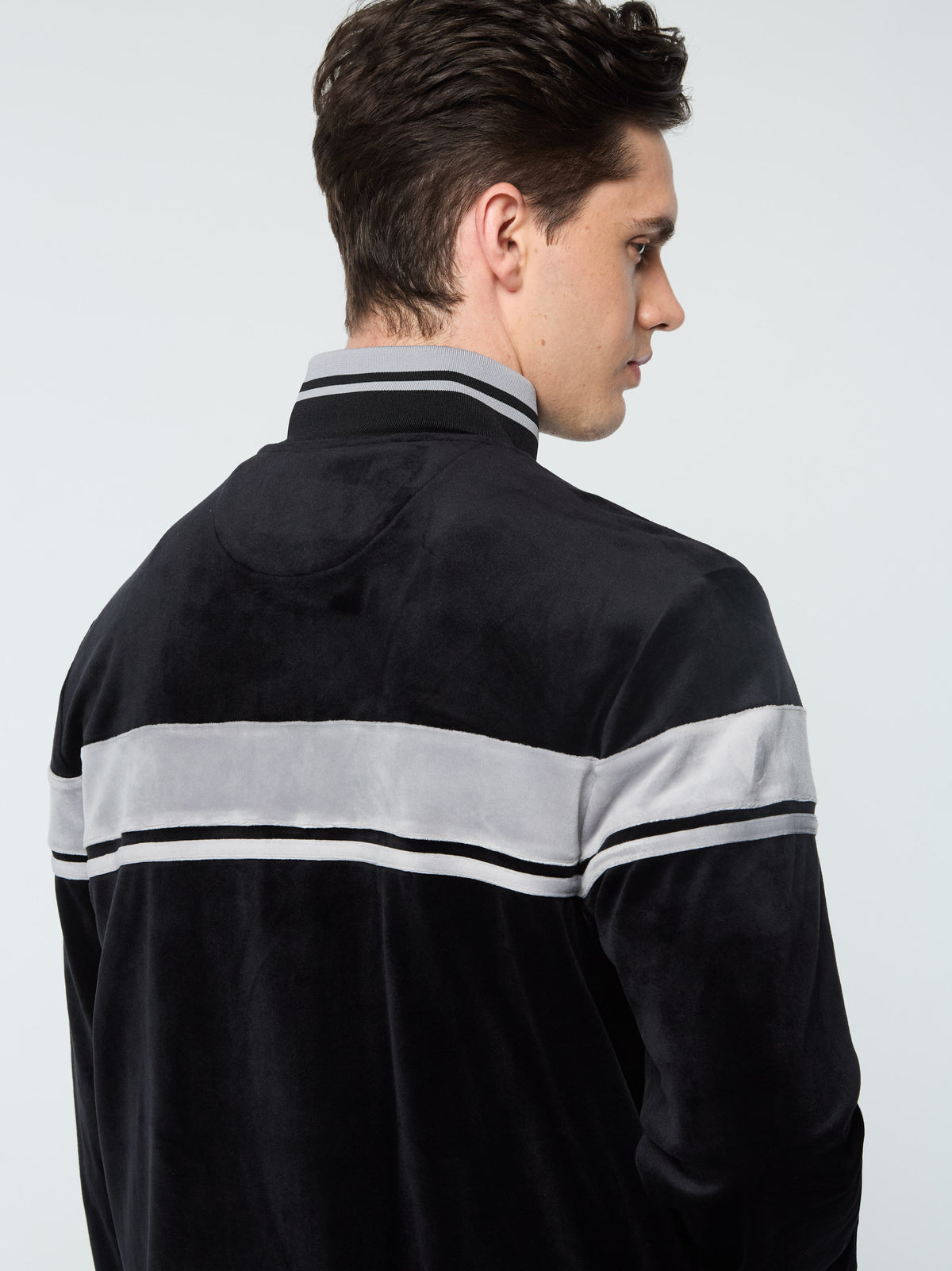 Close-up back view of the collar and chest stripe on the Damarindo Velour Track Jacket in Black Beauty.
