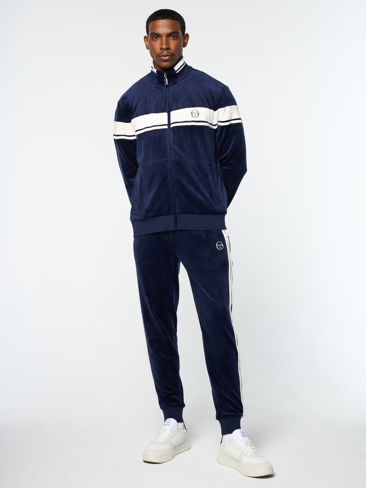 Model wearing the Damarindo Velour Track Jacket and matching pants in Maritime Blue.