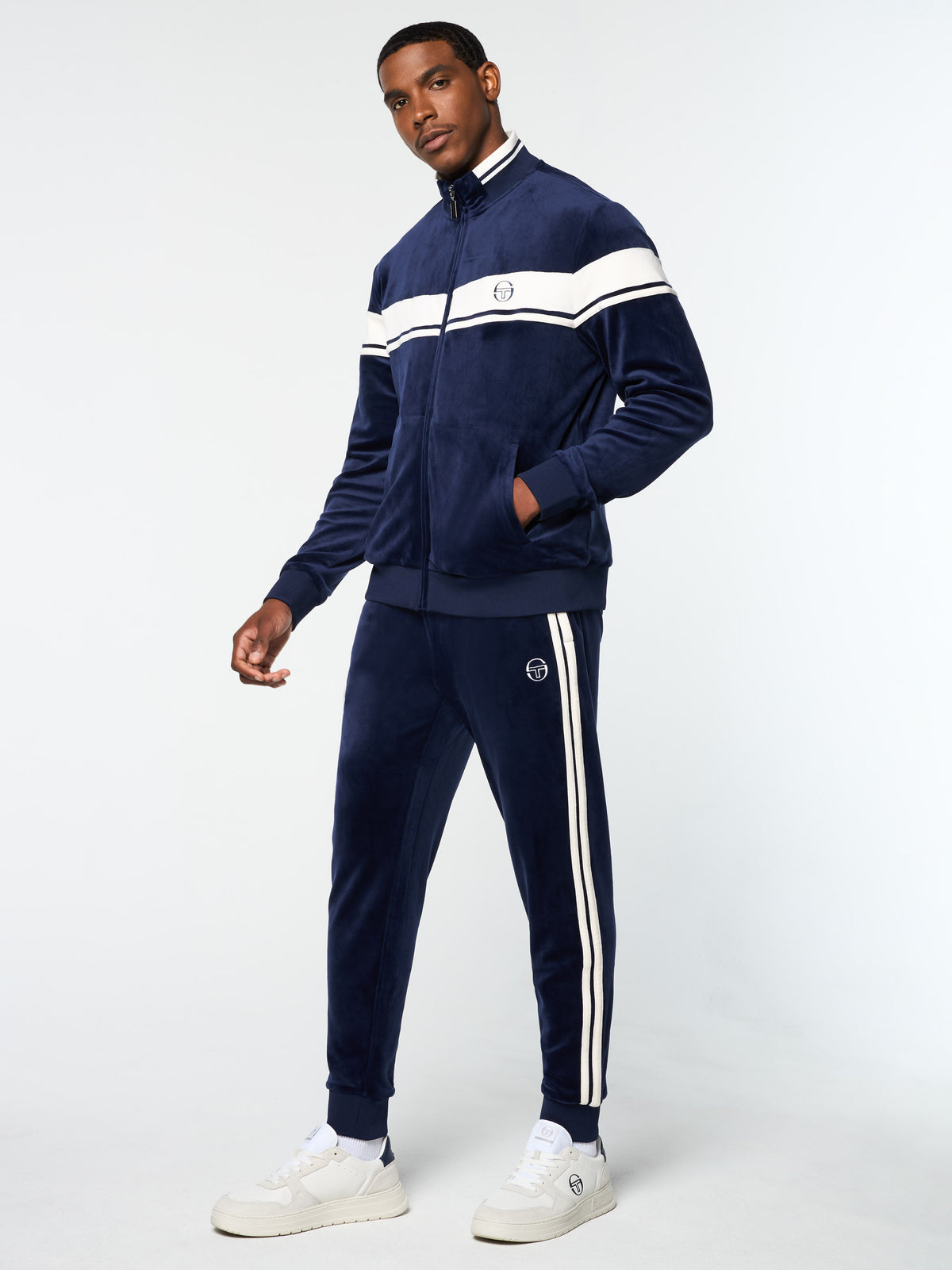 Three-quarter front view of the Damarindo Velour Track Jacket and pants in Maritime Blue.