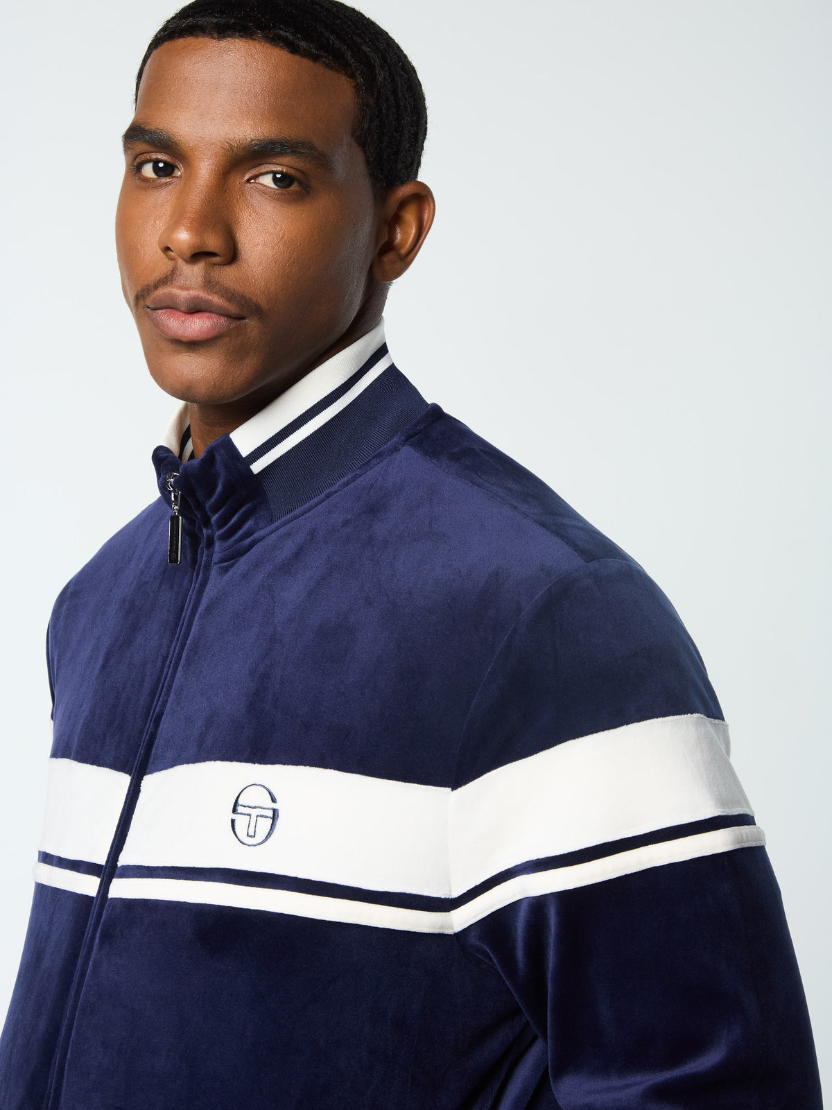 Close-up of the Sergio Tacchini logo and chest stripe on the Damarindo Velour Track Jacket in Maritime Blue.