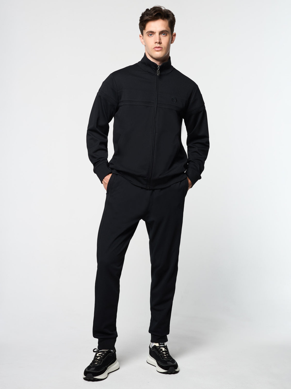 Model wearing the Damarindo Track Jacket Archivio and matching pants in Black.