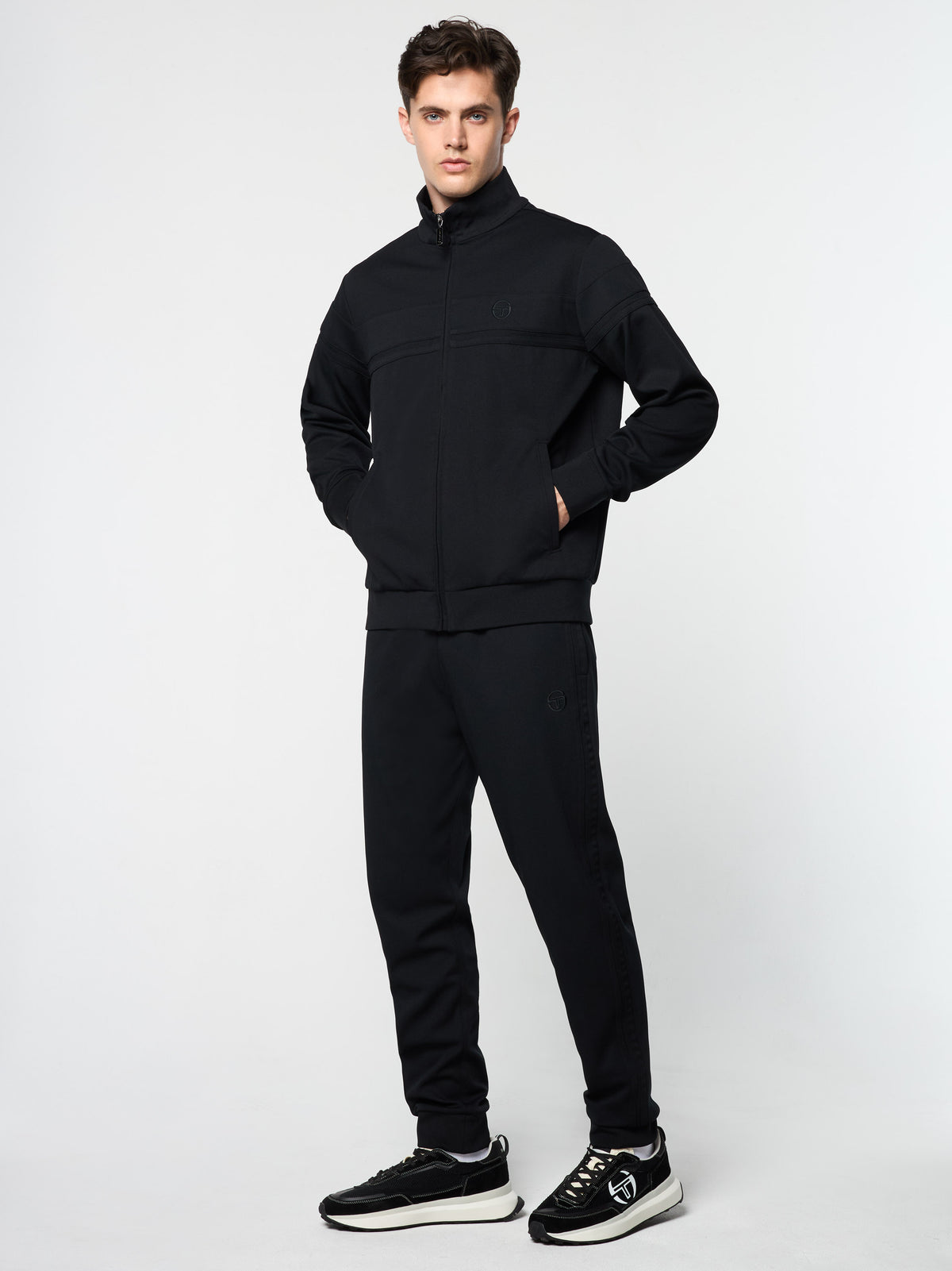 Three-quarter front view of the Damarindo Track Jacket Archivio and pants in Black.