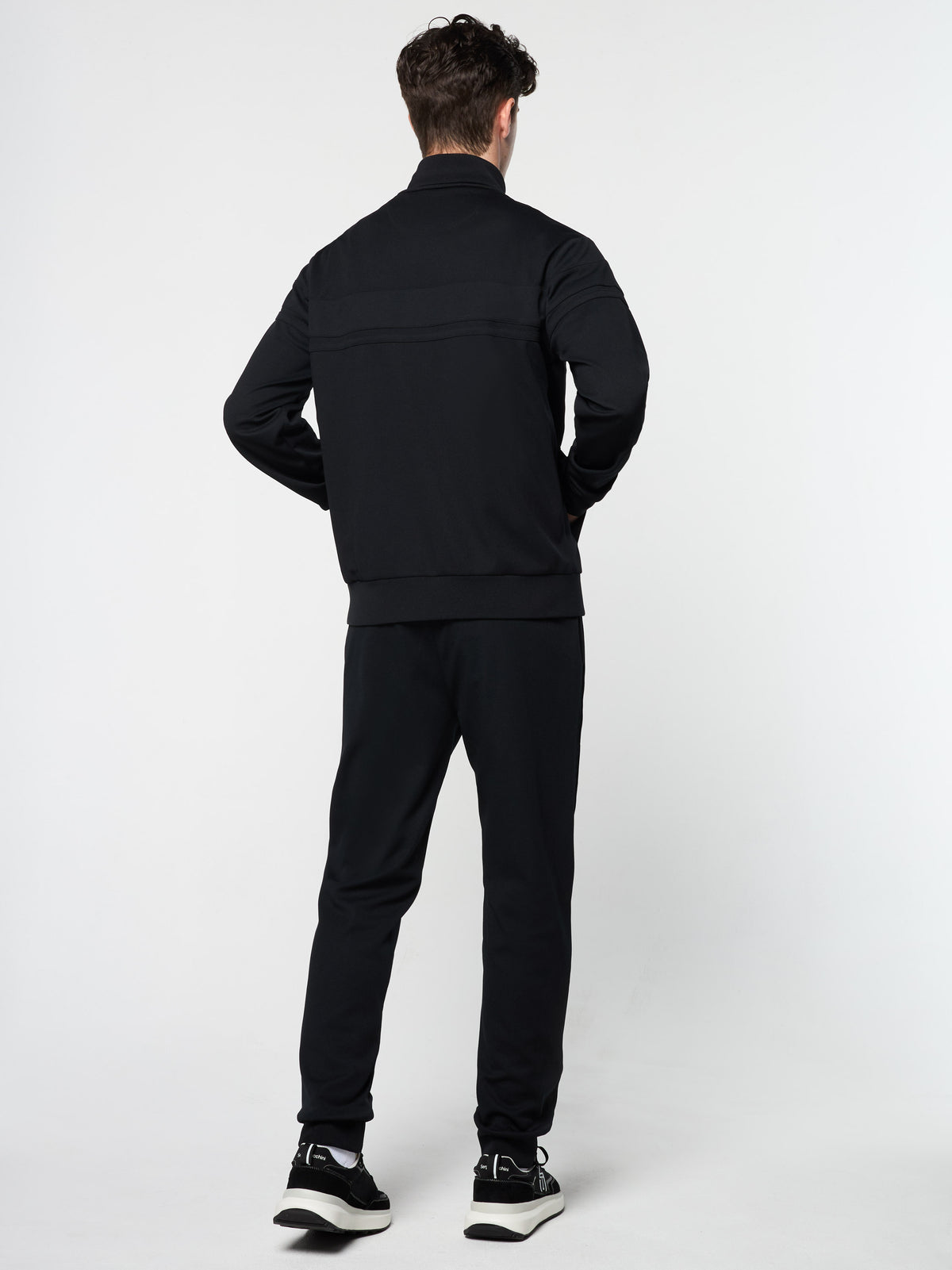 Back view of the Damarindo Track Jacket Archivio and pants in Black.