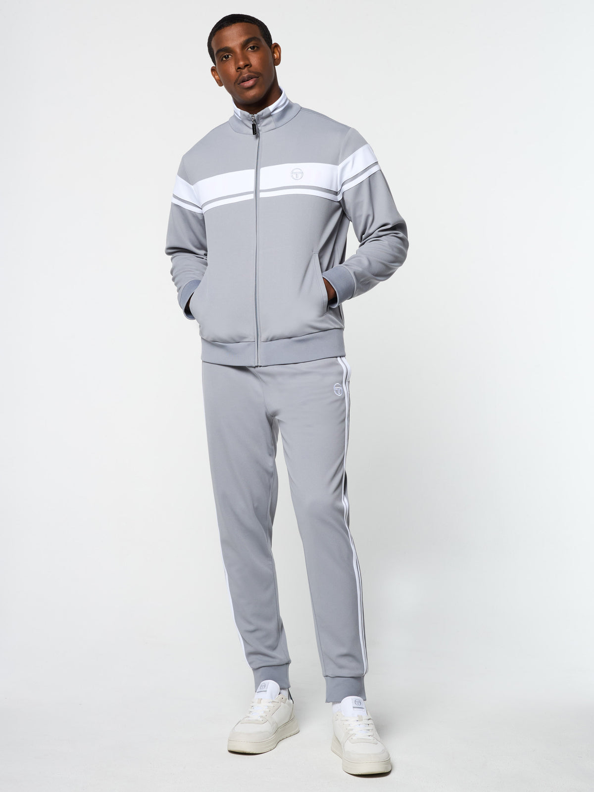 Model wearing the Damarindo Track Jacket Archivio and matching pants in Sleet/White, full body front view.