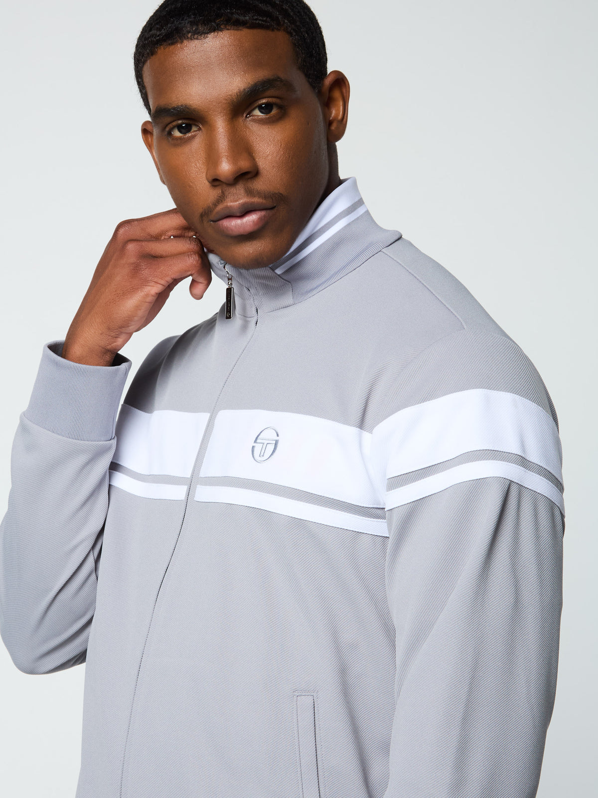 Close-up front profile of the collar, zip, and logo on the Damarindo Track Jacket Archivio in Sleet/White.