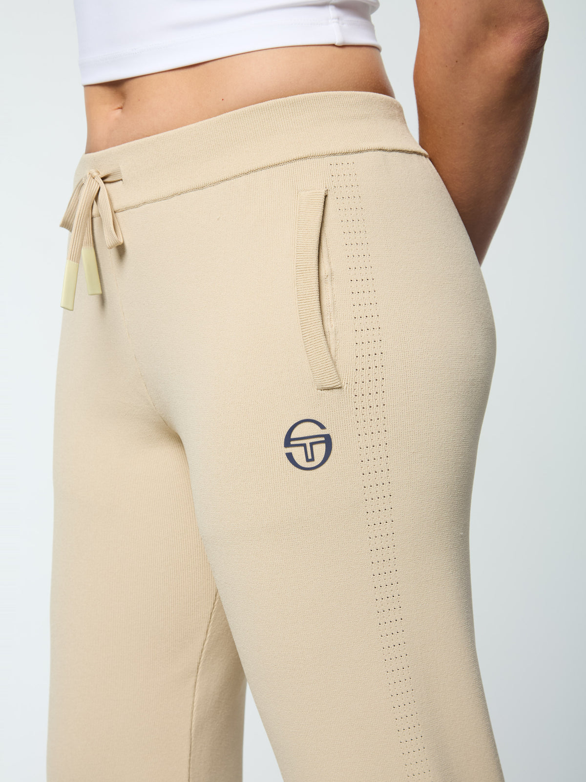 Close-up of the drawstring waistband, pocket, and perforated side stripe on the Rosolina Track Pant in Humus.