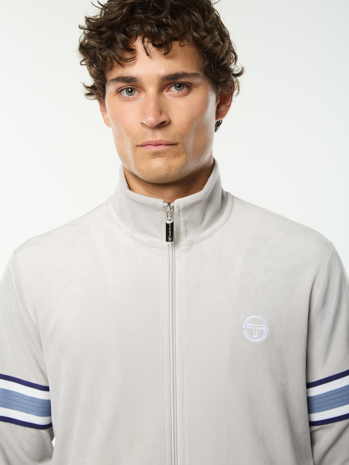Close-up front portrait of the stand collar and embroidered logo on the Linera Velour Track Jacket in Quiet Gray.