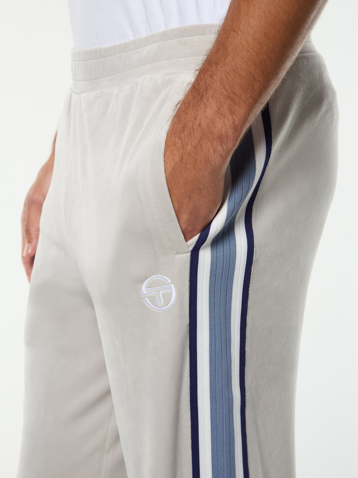 Close-up of the waistband, pocket and embroidered logo on the Linera Velour Track Pant in Quiet Gray.