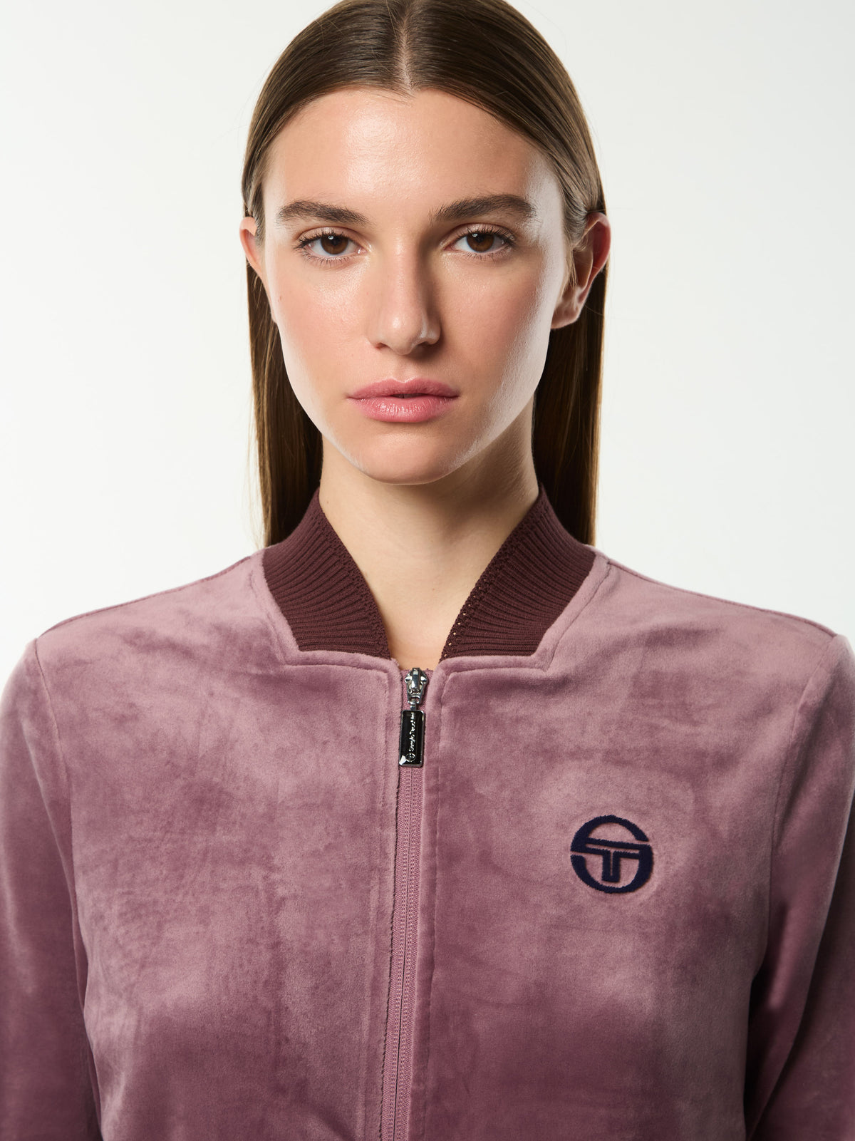 Close-up front portrait of the ribbed collar and embroidered logo on the Dalia Velour Track Jacket in Grape Shake.