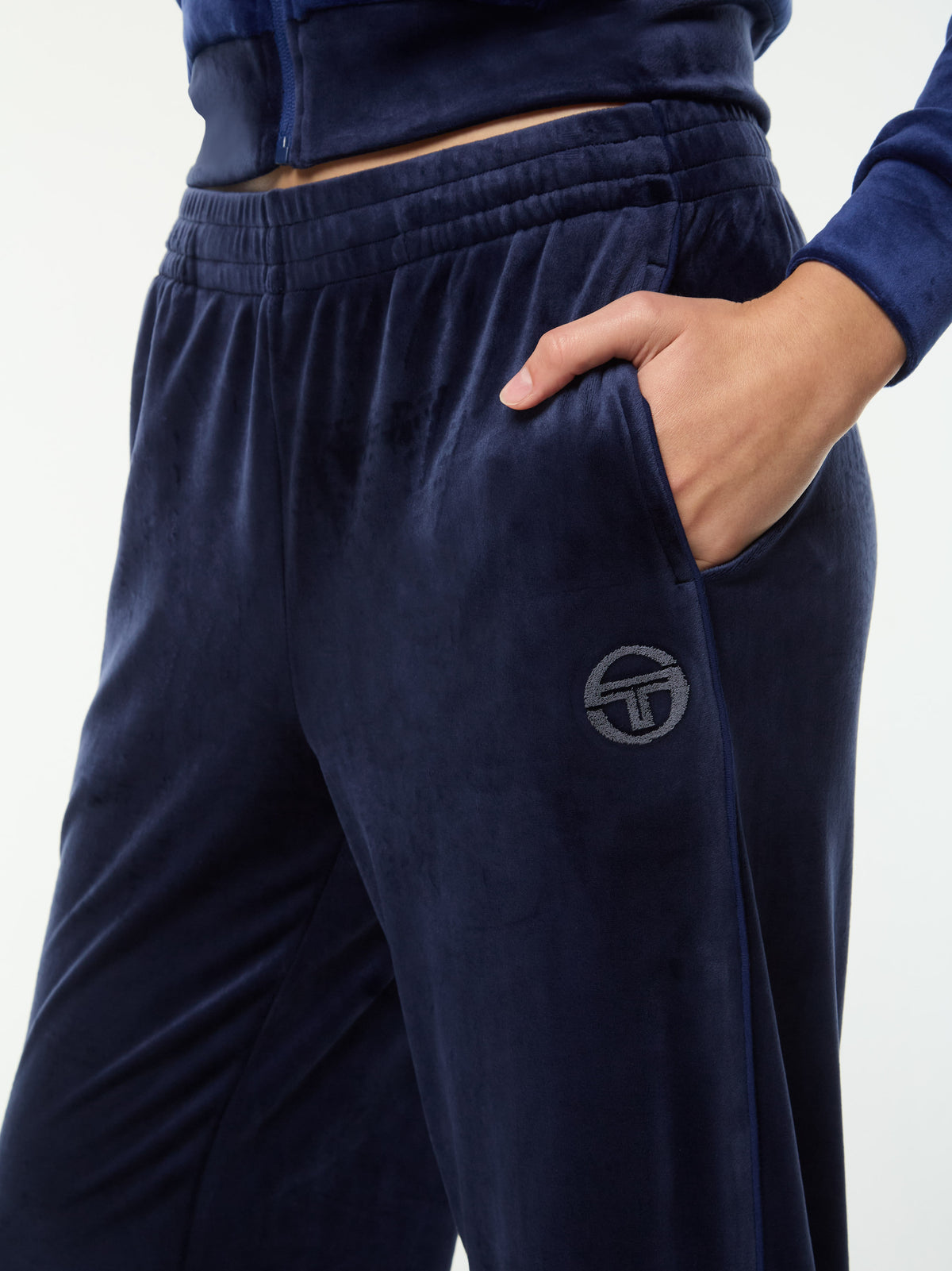 Close-up of the elastic waistband, pocket and tonal logo on the Dalia Velour Track Pant in Maritime Blue.