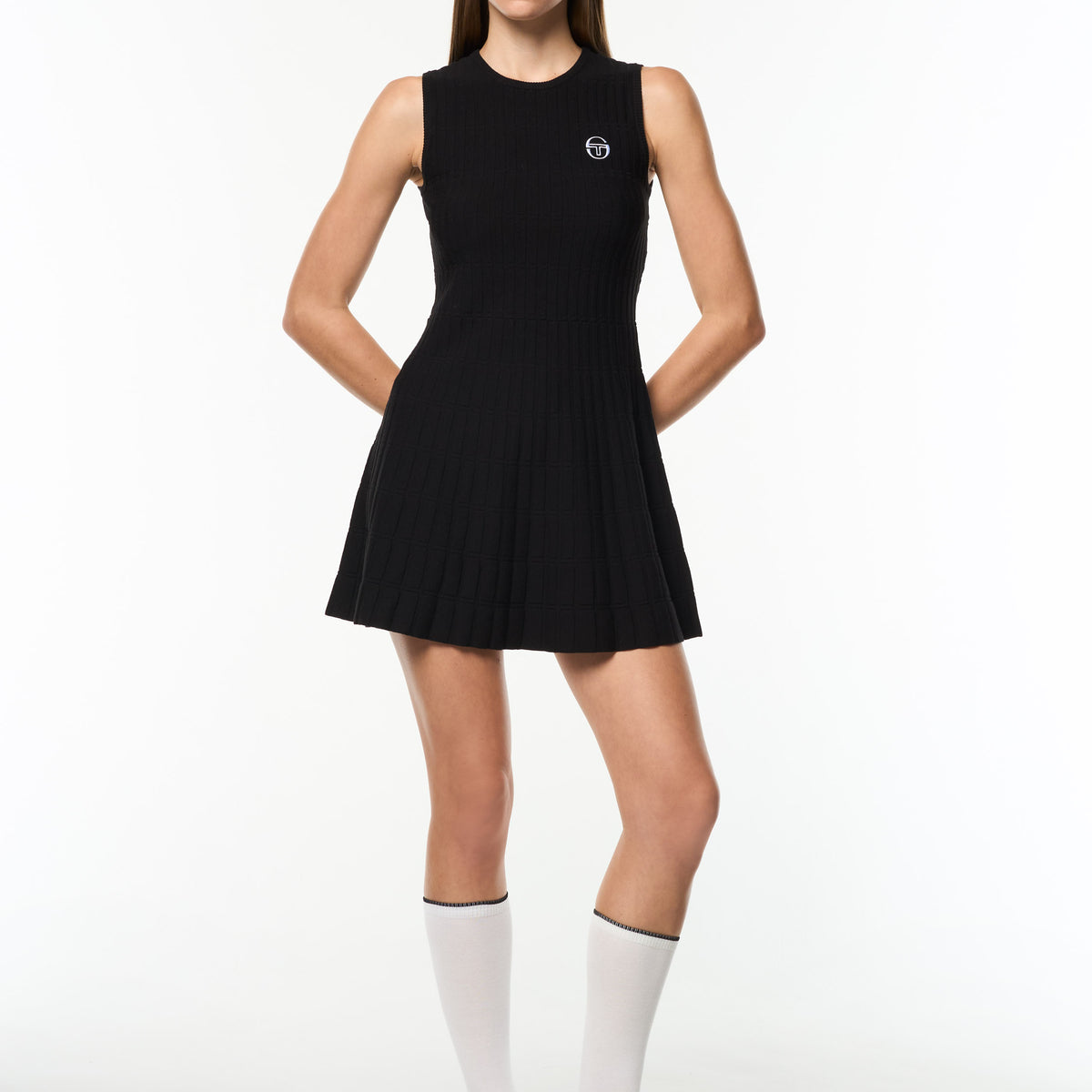 Model wearing the Nifea Knit Dress in Black Beauty, a sleeveless ribbed tennis dress with flared skirt, full body front view.
