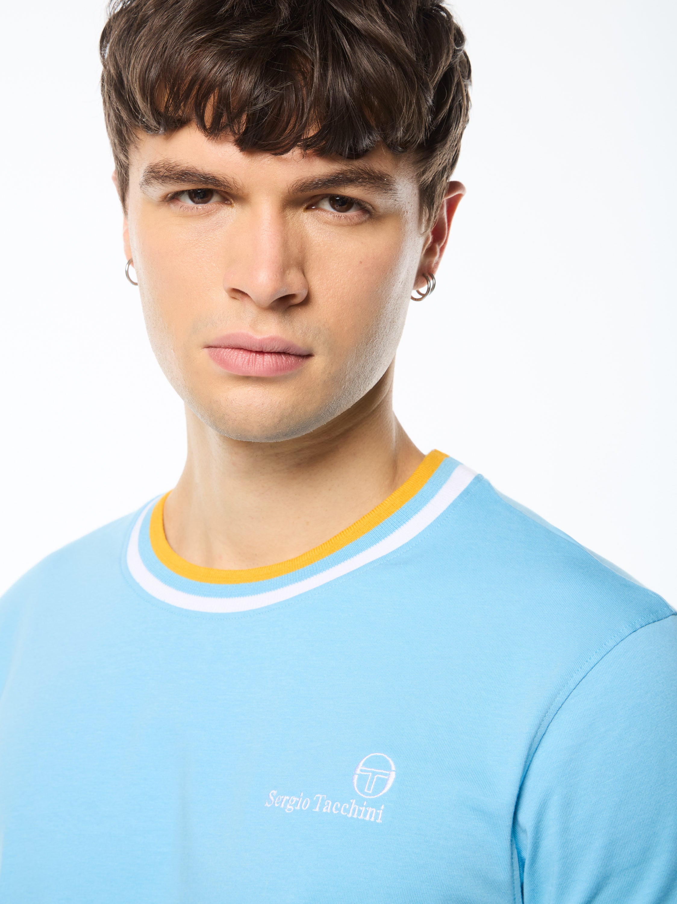 Man wearing a baby blue shirt with a yellow and white stripe around collar.