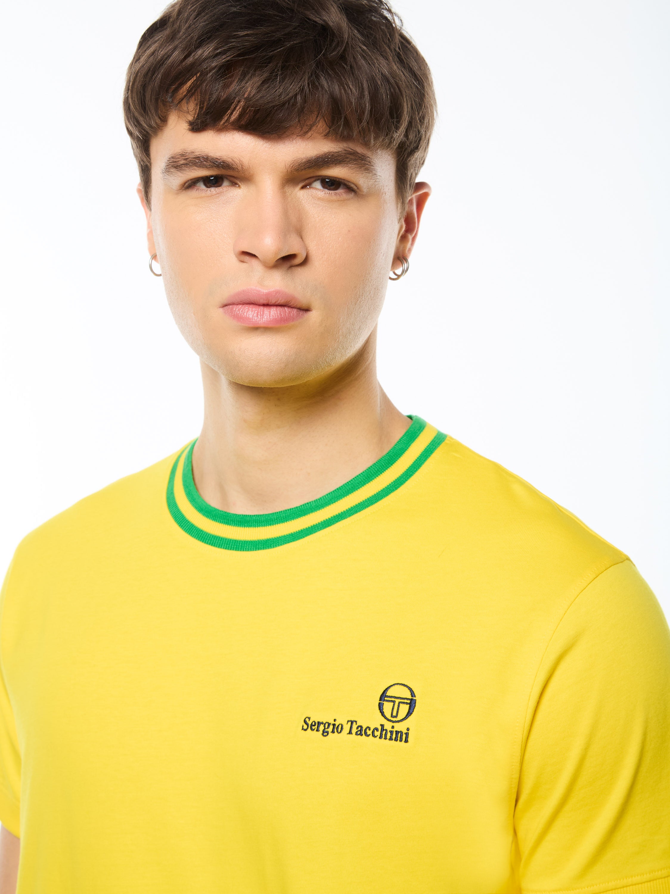 Man wearing a yellow shirt with green stripes around collar.