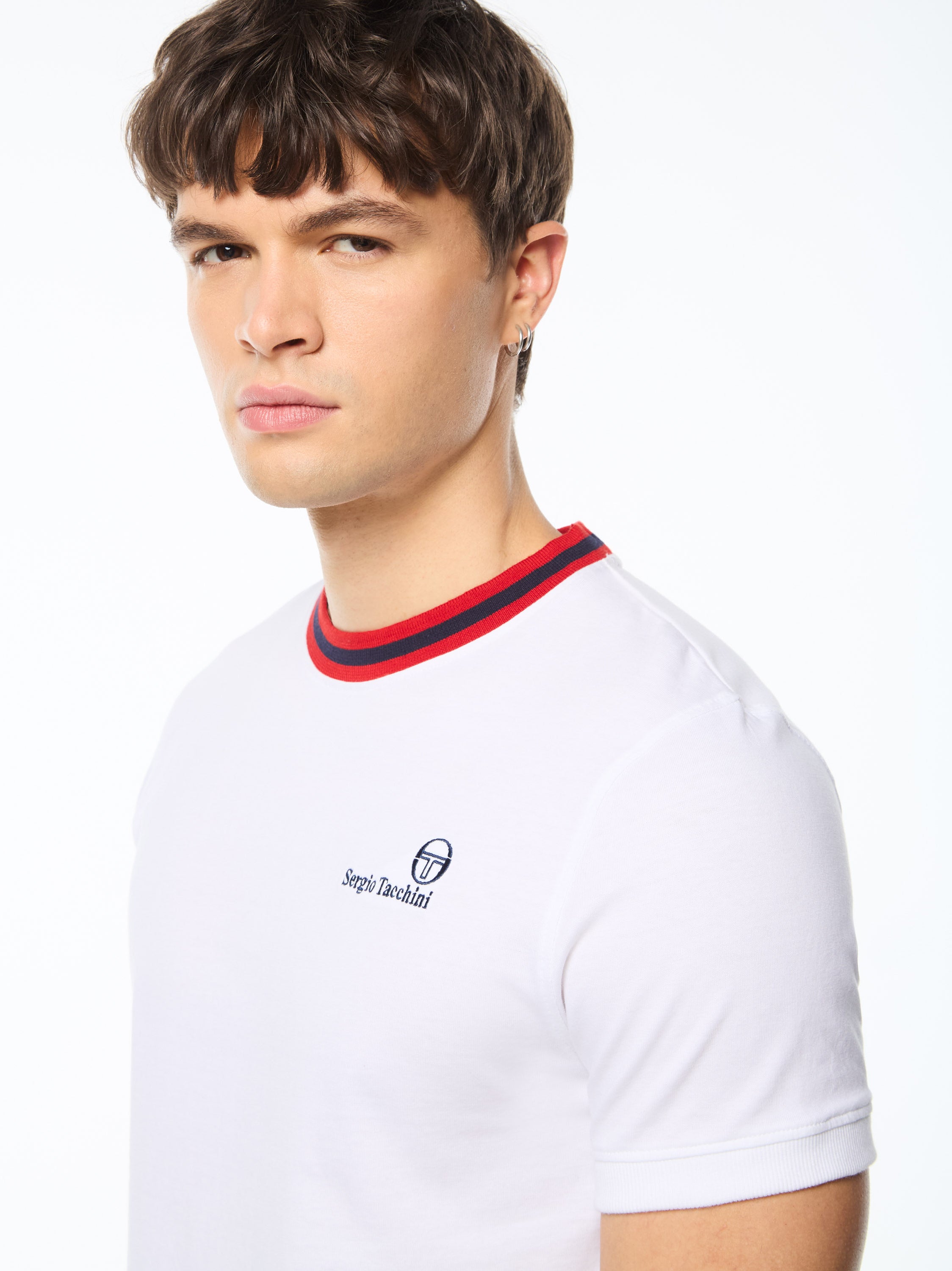 Man wearing a white shirt with red and black stripes around collar.