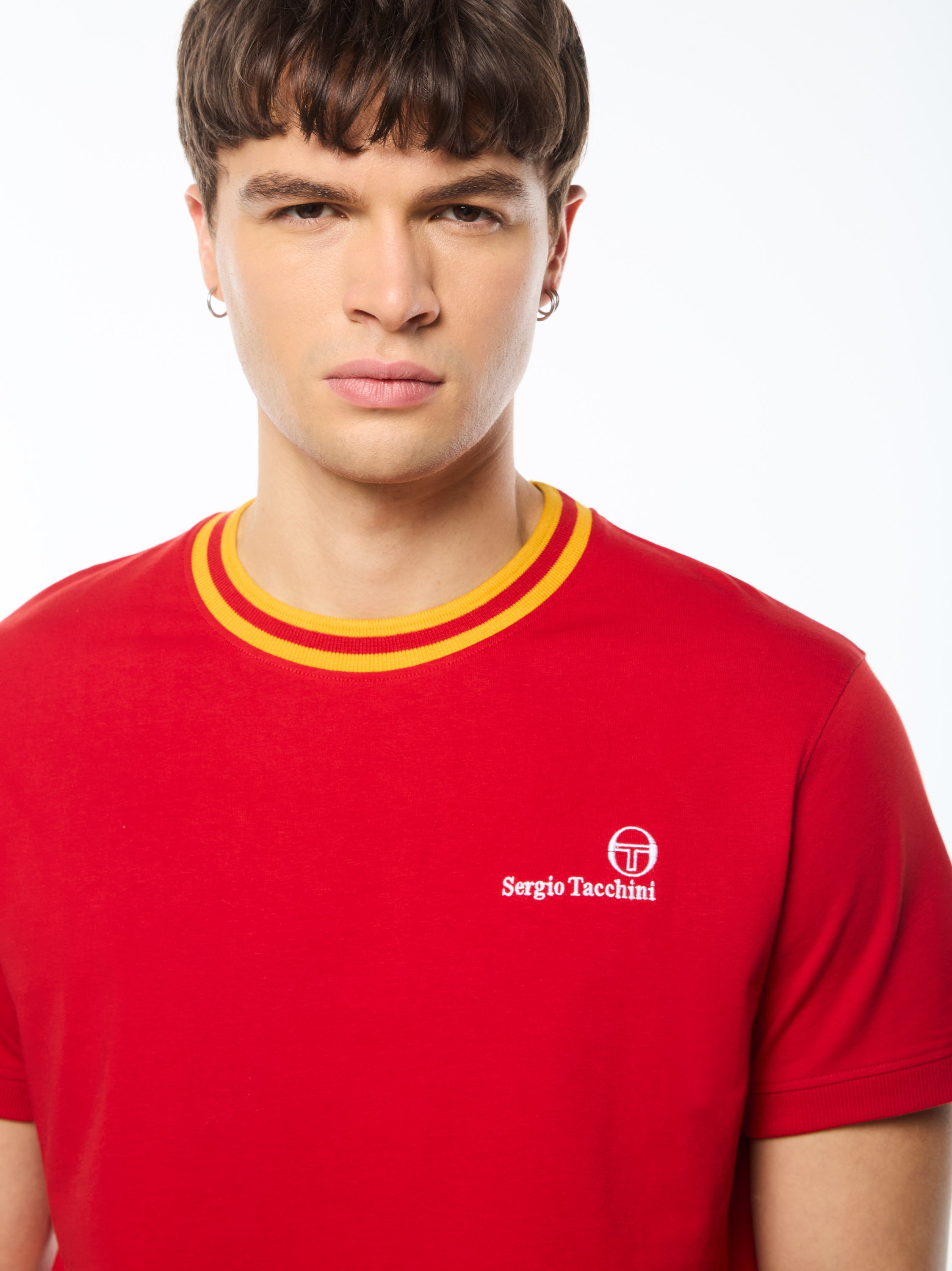 Man wearing a red shirt with a yellow and red stripe around collar.