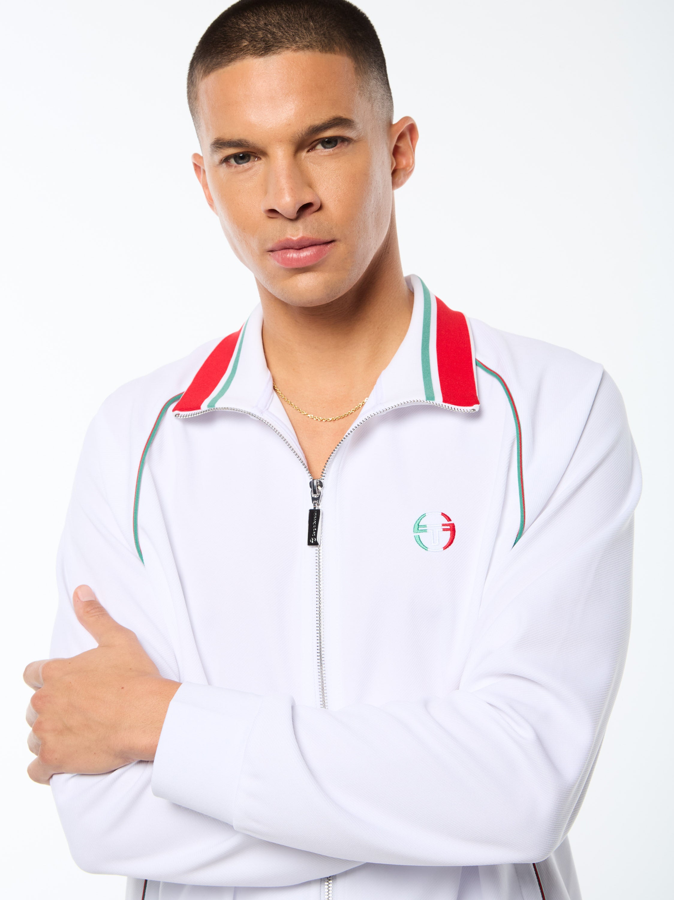 Man wearing a white track jacket with red and green accent details.