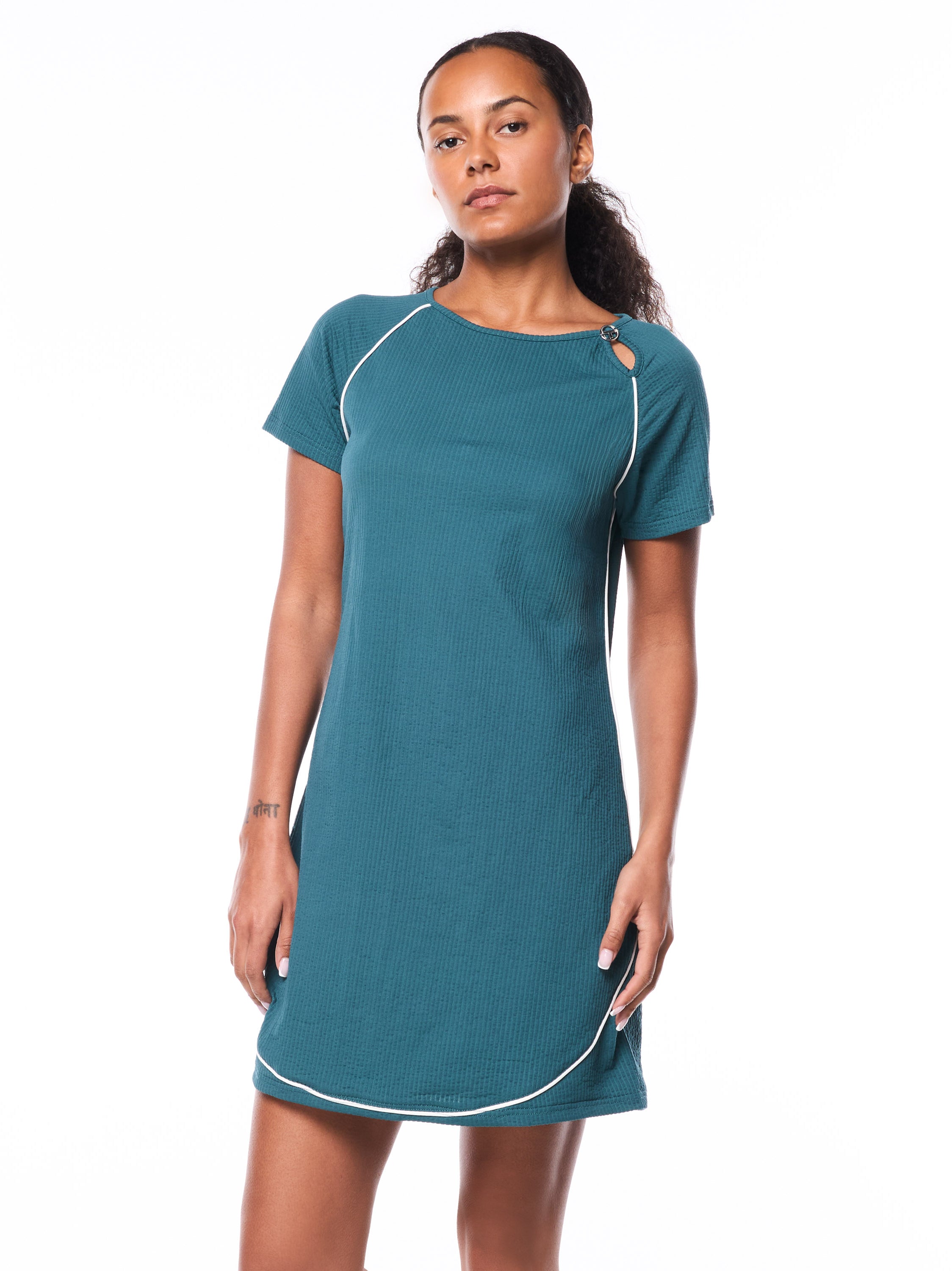 A woman wearing a teal ribbed dress with keyhole detail on shoulder and white piping around the dress.