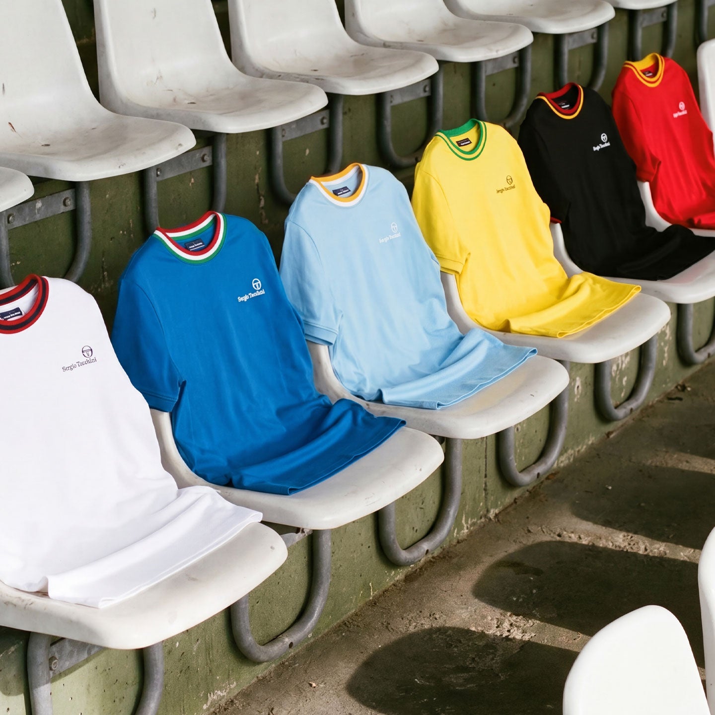 Multi colored shirts sitting in stadium seats