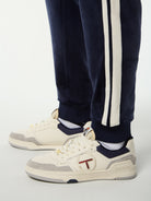 Close-up of the ribbed cuff and side stripes on the Damarindo Velour Track Pant in Maritime Blue.