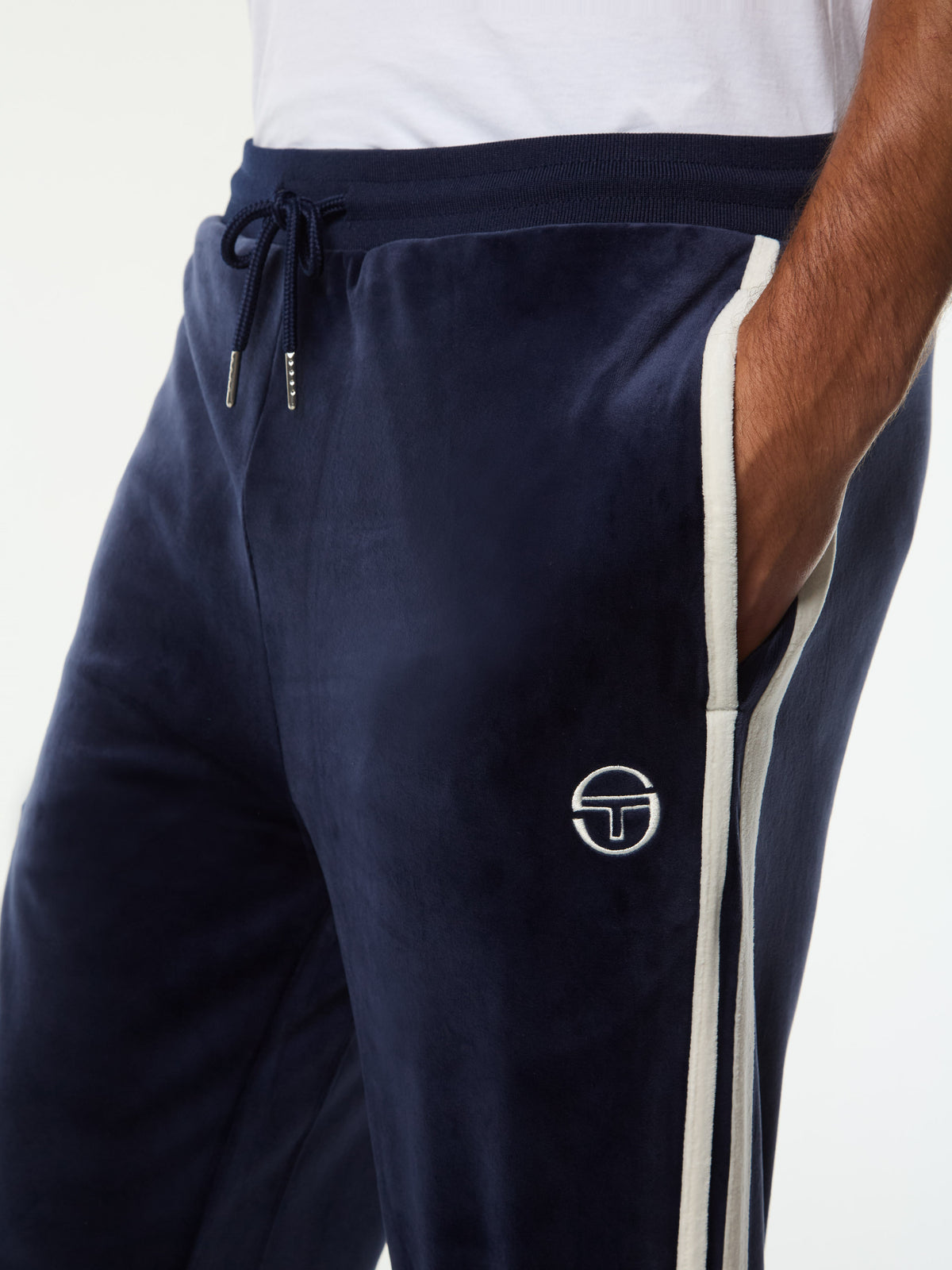 Close-up of the drawstring waistband and embroidered logo on the Damarindo Velour Track Pant in Maritime Blue.