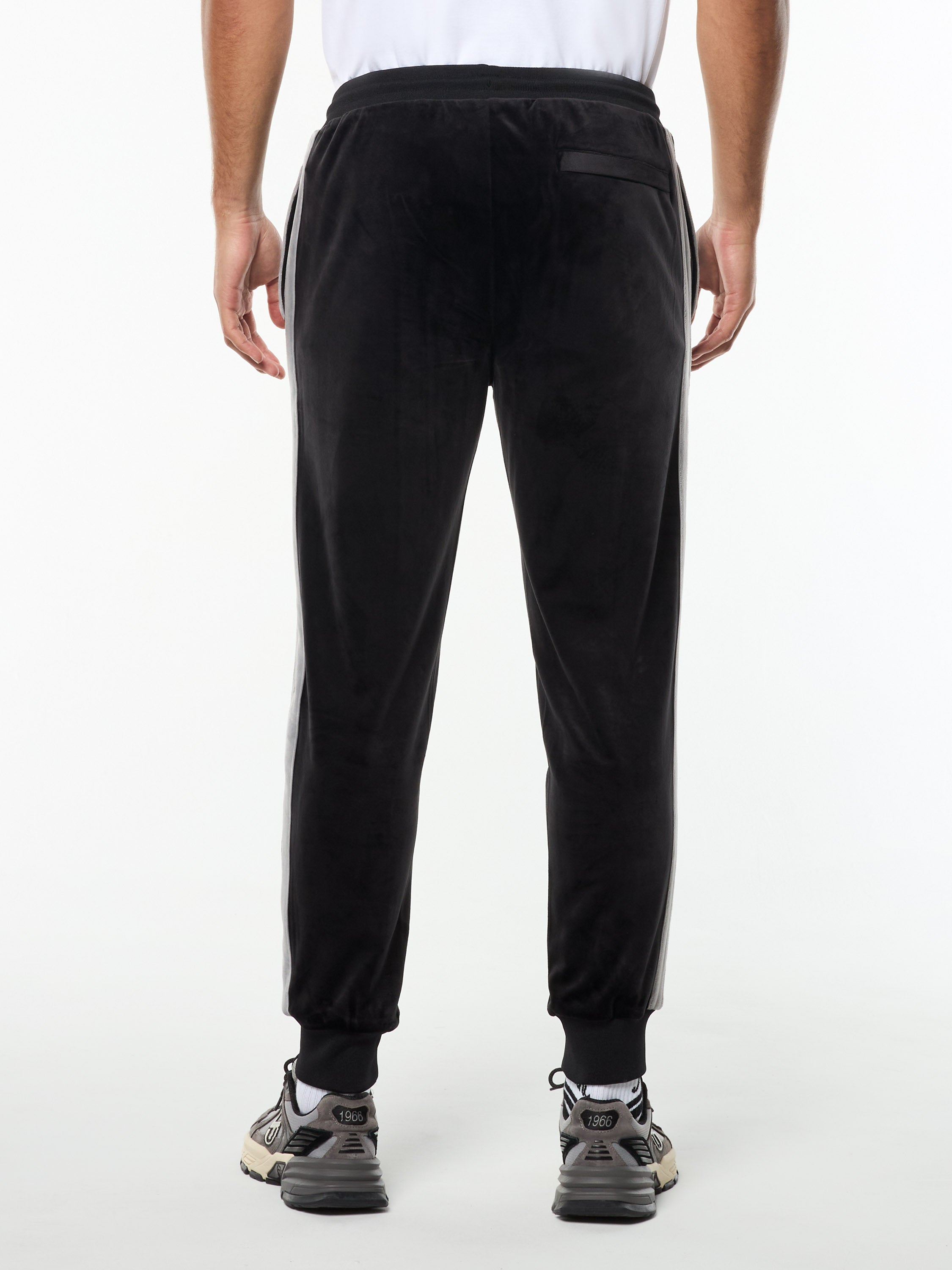 Back view of the Damarindo Velour Track Pant in Black Beauty, showing the zip back pocket and ribbed cuffs.