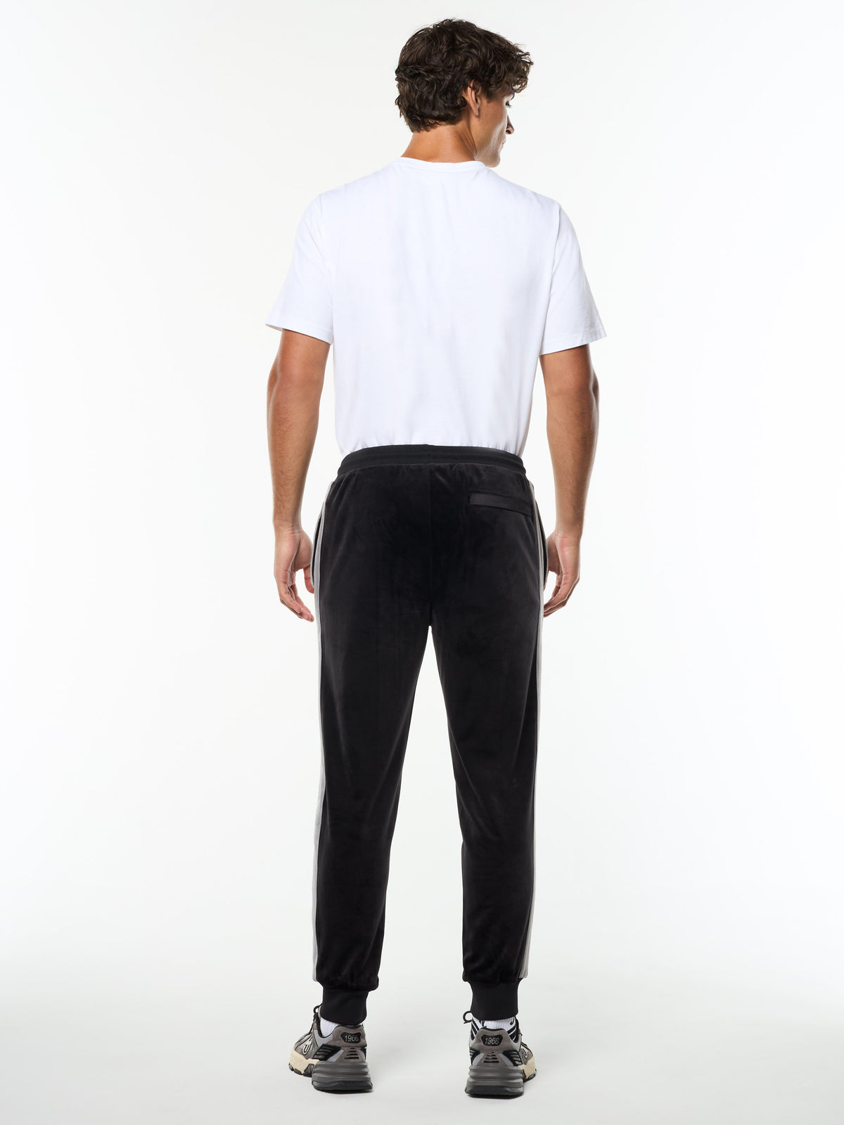 Full body back view of the Damarindo Velour Track Pant in Black Beauty worn with a white tee.
