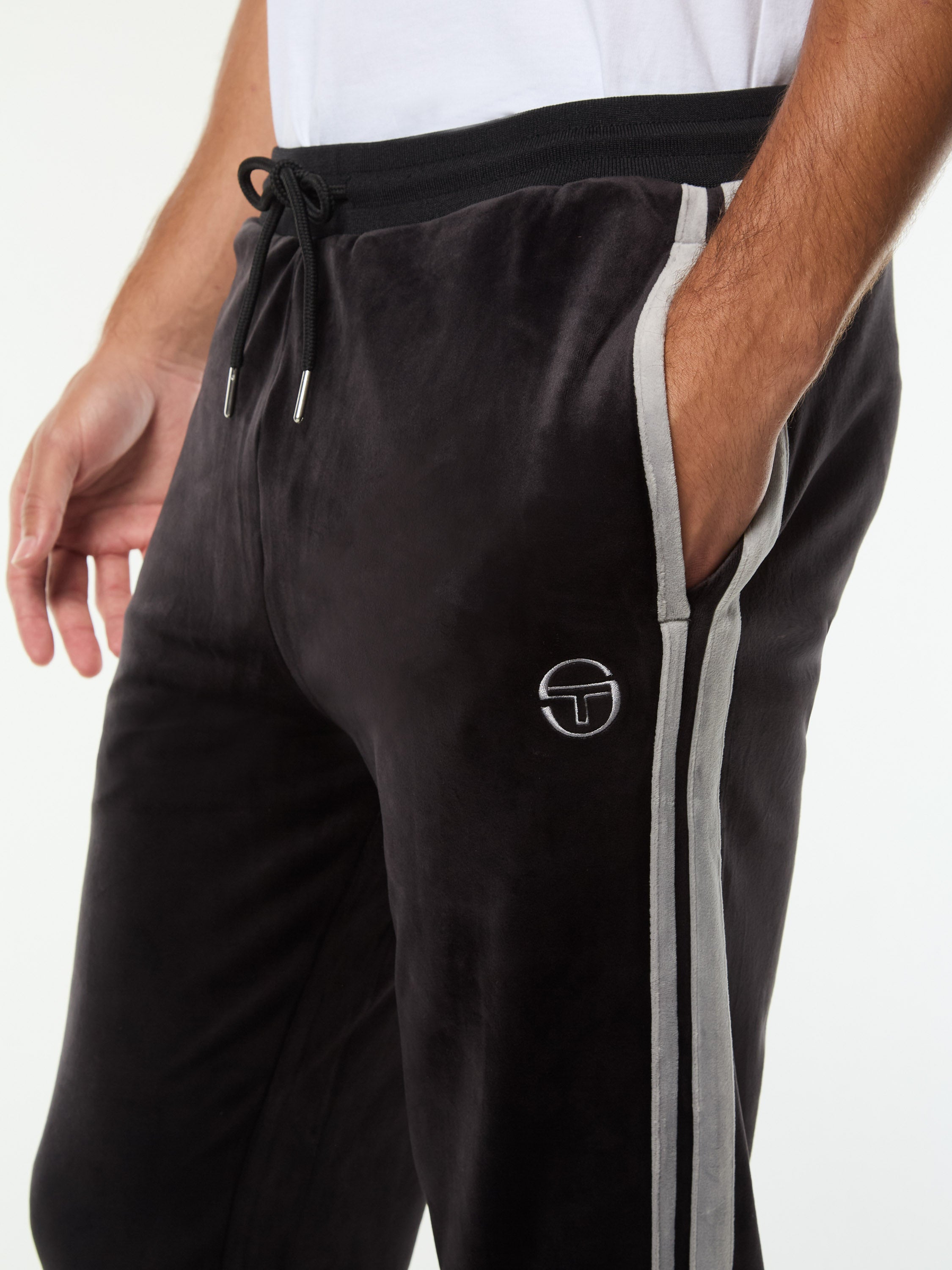 Close-up of the drawstring waistband, side stripe and embroidered logo on the Damarindo Velour Track Pant in Black Beauty.