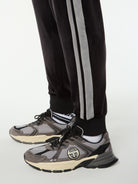 Close-up of the ribbed cuff and gray side stripes on the Damarindo Velour Track Pant in Black Beauty.