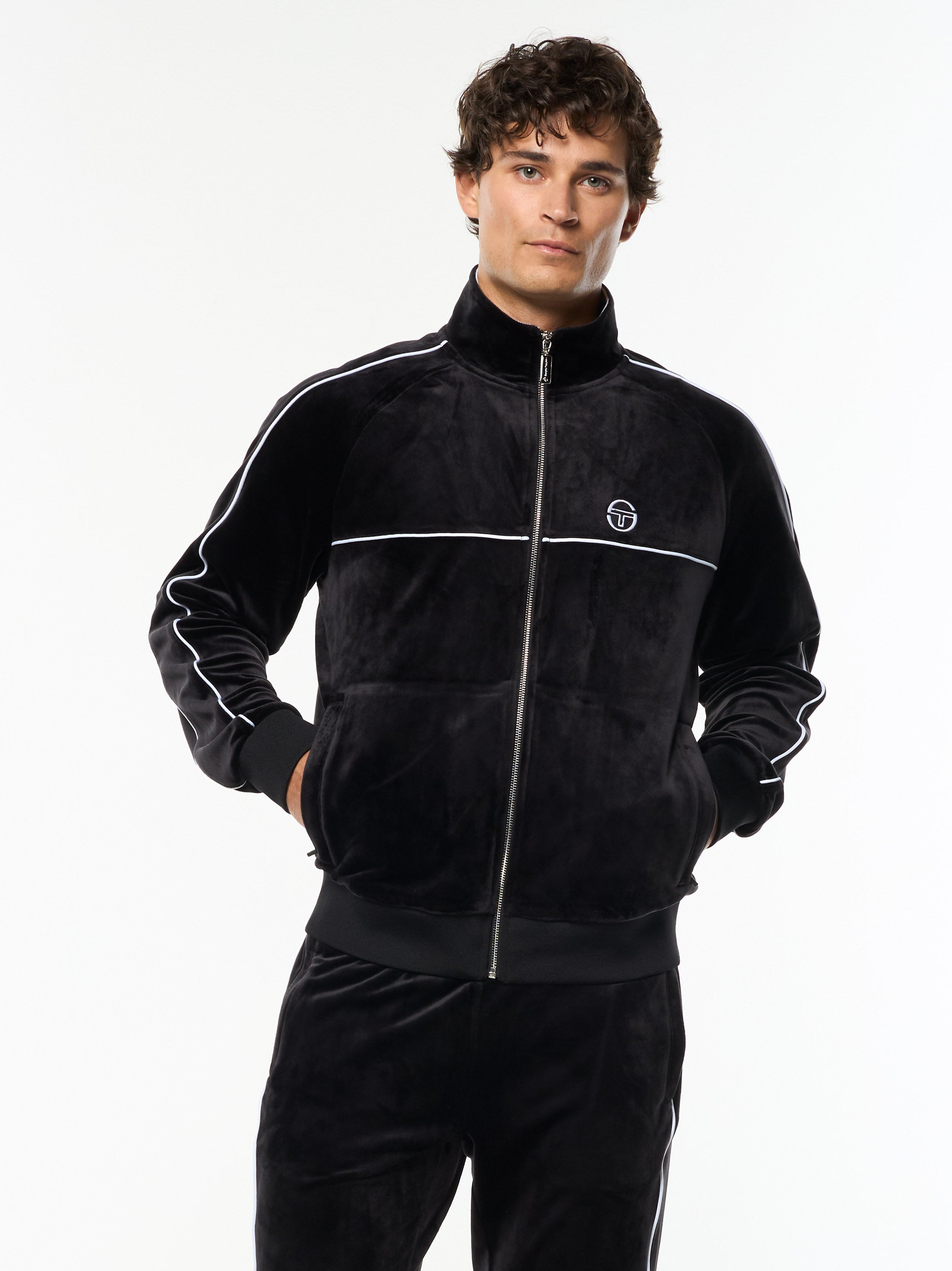 Model wearing the Lioni Velour Track Jacket in Black Beauty with white piping, front upper body view.