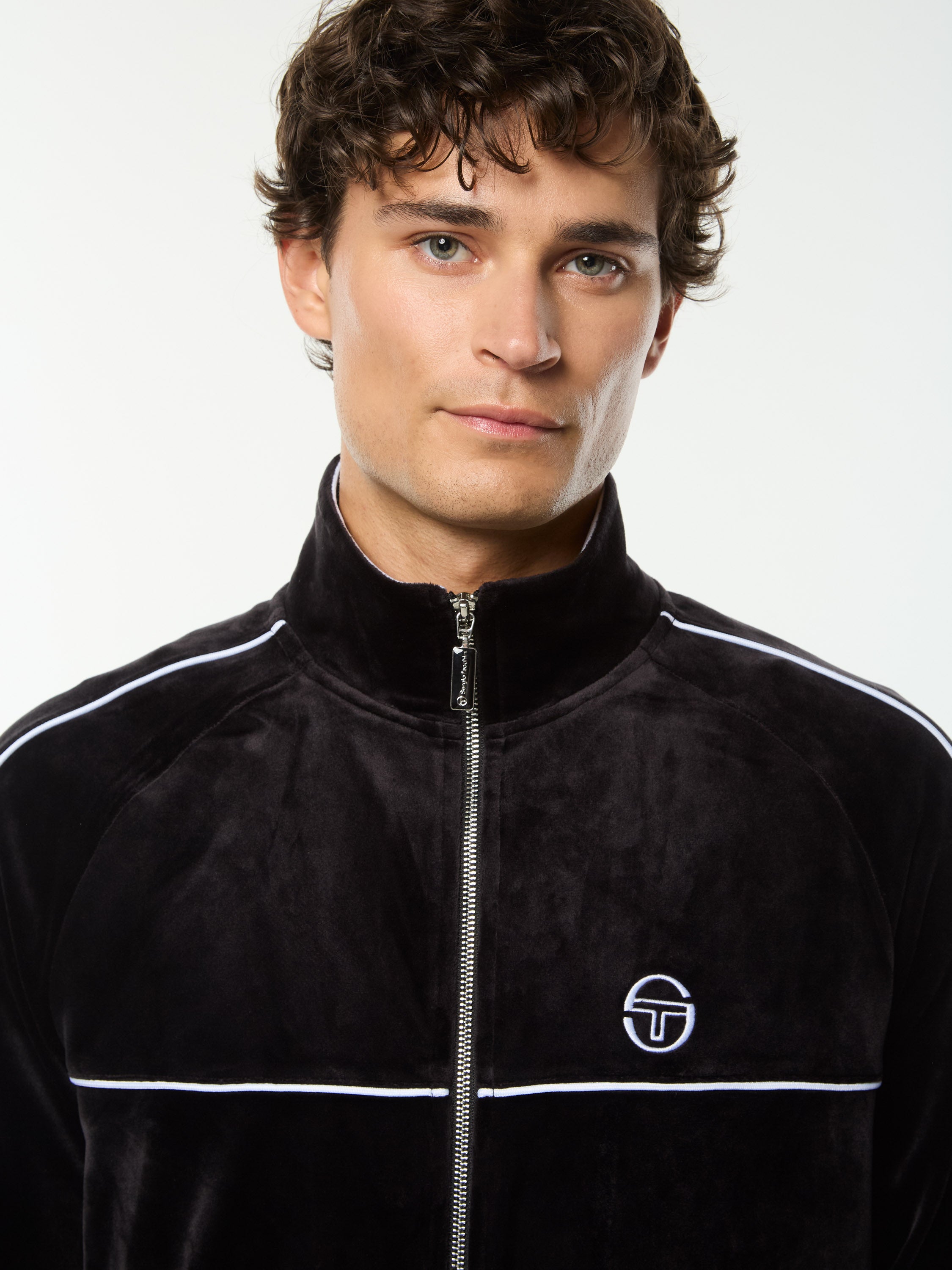 Close-up front portrait of the stand collar and embroidered logo on the Lioni Velour Track Jacket in Black Beauty.