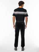 Full body back view of the Lioni Velour Track Pant in Black Beauty with a striped tee.