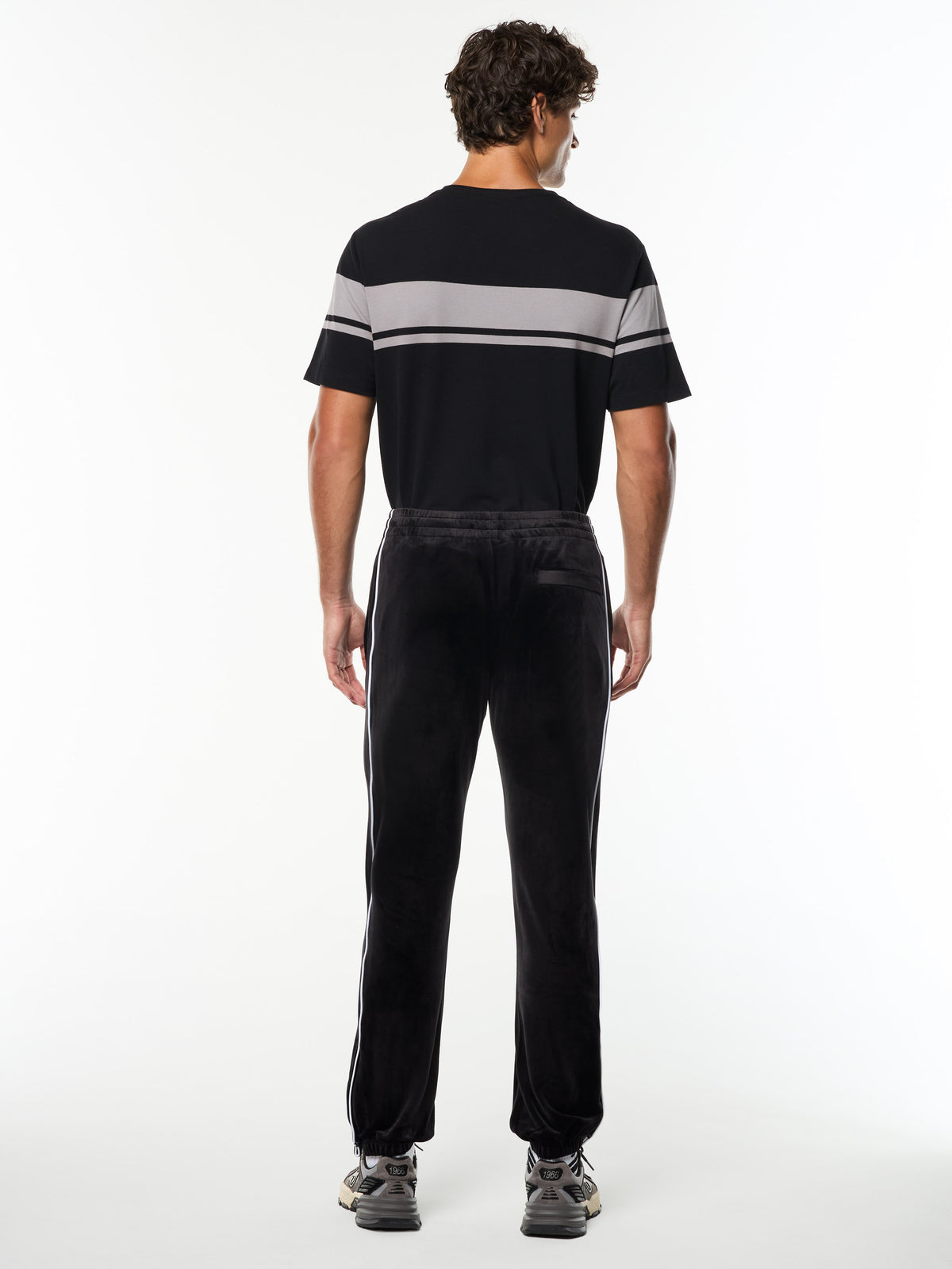Full body back view of the Lioni Velour Track Pant in Black Beauty with a striped tee.