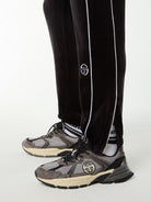 Close-up of the ribbed cuff, white piping and embroidered logo on the Lioni Velour Track Pant in Black Beauty.