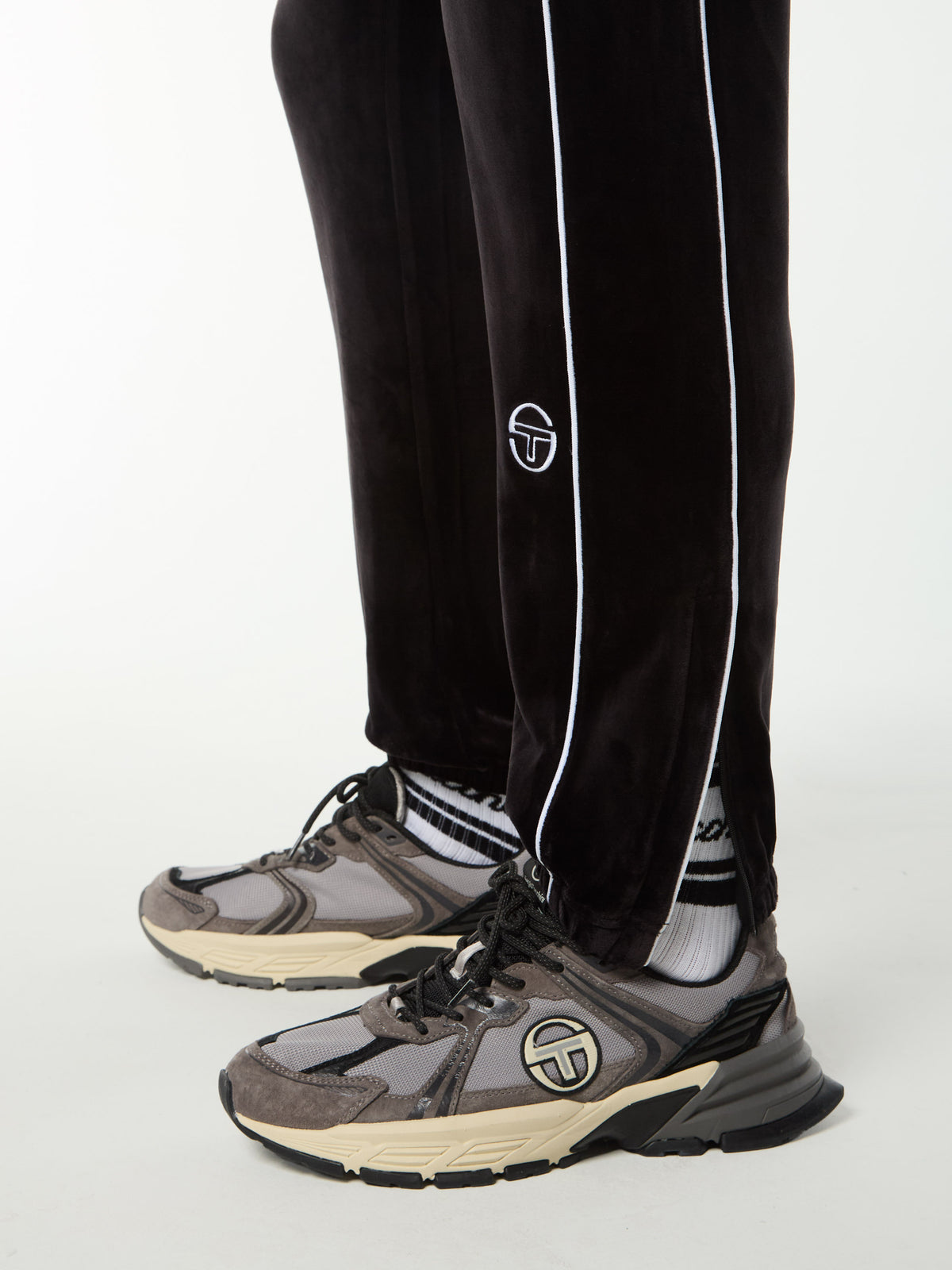 Close-up of the ribbed cuff, white piping and embroidered logo on the Lioni Velour Track Pant in Black Beauty.