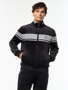 Model wearing the Damarindo Velour Track Jacket in Black Beauty with a gray chest stripe, front upper body view.