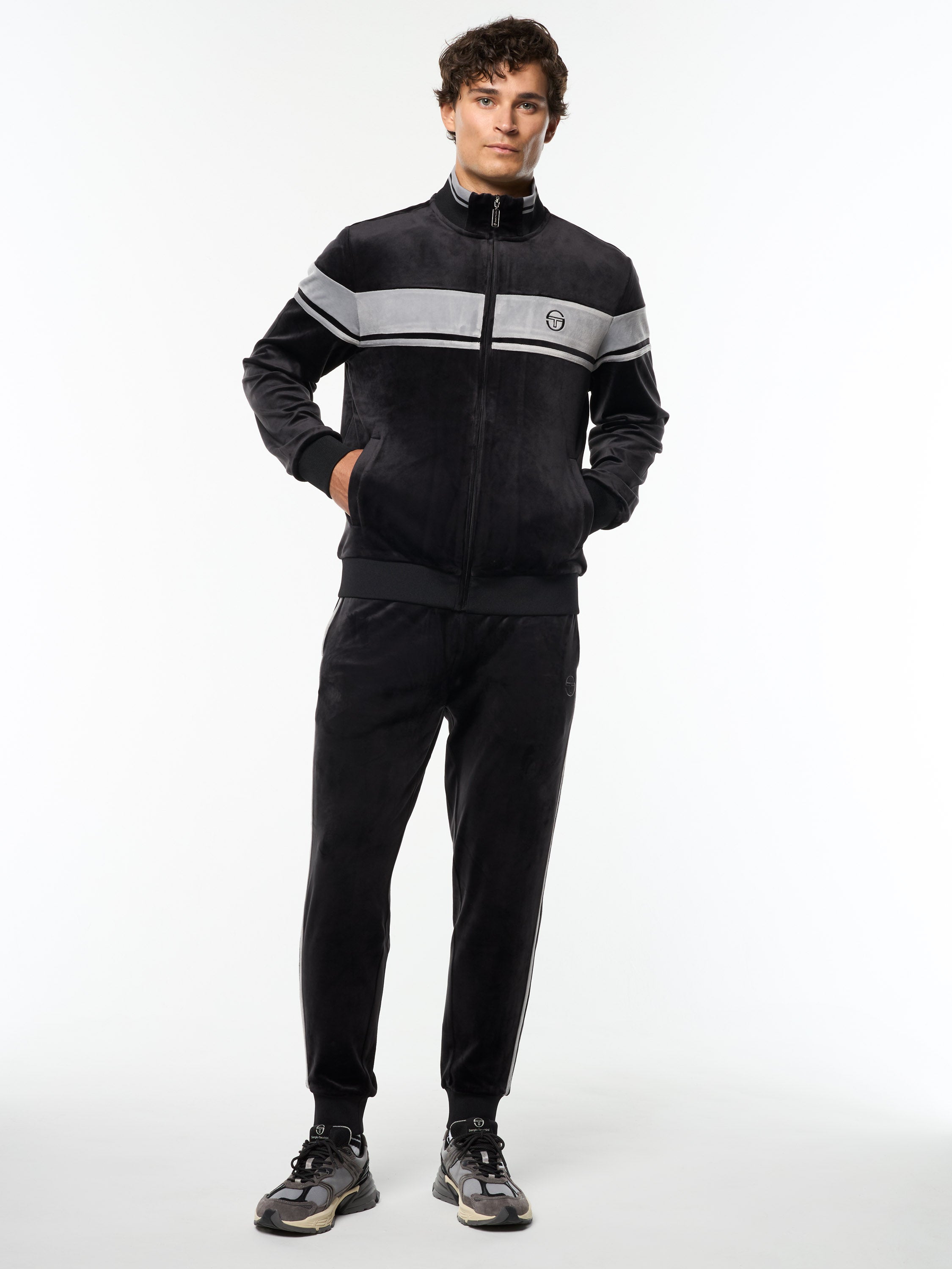 Model wearing the Damarindo Velour Track Jacket and matching pants in Black Beauty, full body front view.