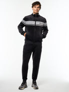 Model wearing the Damarindo Velour Track Jacket and matching pants in Black Beauty, full body front view.