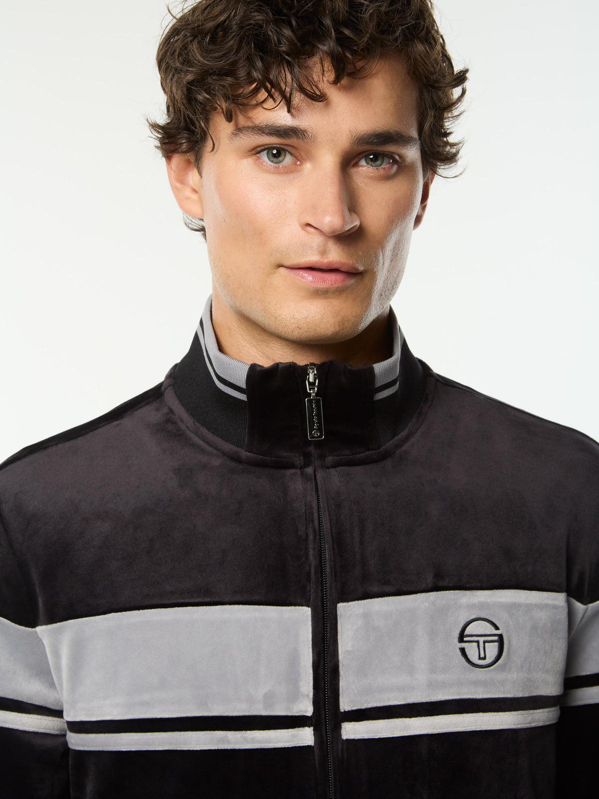 Close-up front portrait of the stand collar and embroidered logo on the Damarindo Velour Track Jacket in Black Beauty.