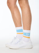 Man wearing white socks with baby blue and yellow stripes.