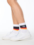 Man wearing white socks with black, red, and yellow stripes.