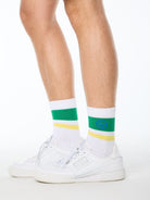 Man wearing white socks with green and yellow stripes.